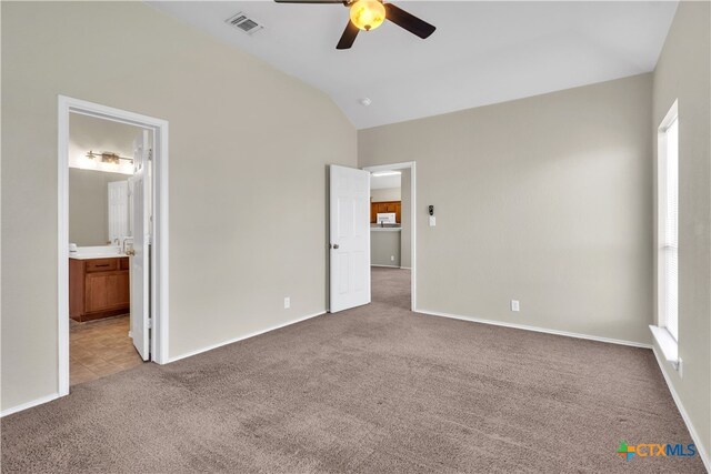 unfurnished bedroom featuring lofted ceiling, multiple windows, ceiling fan, and ensuite bath