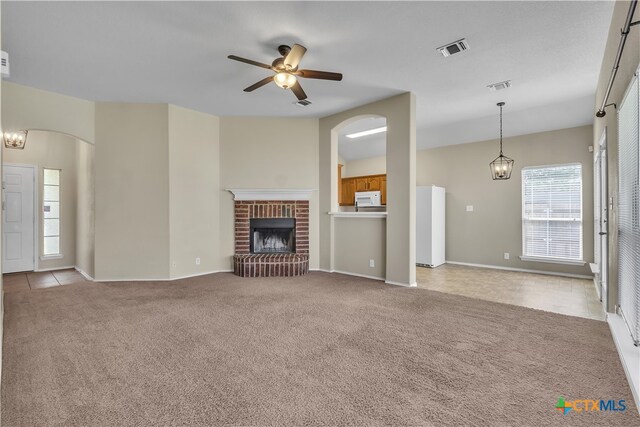 unfurnished living room with a brick fireplace, light carpet, and ceiling fan