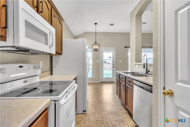 kitchen featuring decorative light fixtures, sink, white appliances, and vaulted ceiling