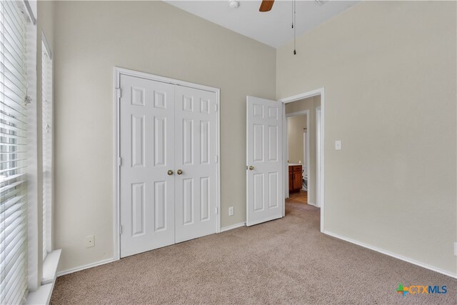 unfurnished bedroom with a closet, light colored carpet, and ceiling fan