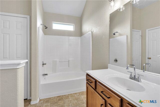 bathroom featuring vanity, washtub / shower combination, and vaulted ceiling