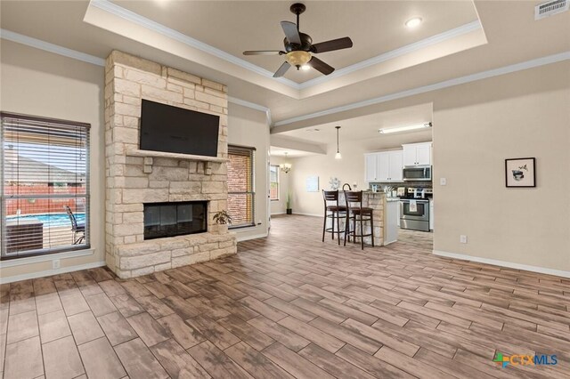 2017 Wagon Gap Rd, Temple, TX 76502 - living room with light wood-style floors, a ceiling fan, a tray ceiling, visible vents, and ornamental molding