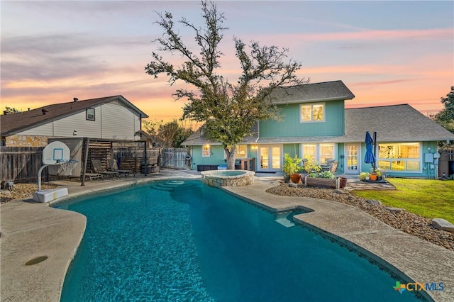 view of pool with a fenced backyard, a pool with connected hot tub, a yard, french doors, and a patio area