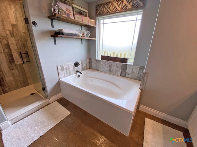 full bath featuring a tub with jets, a stall shower, and baseboards