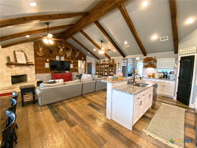 kitchen with sink, vaulted ceiling with beams, dark hardwood / wood-style floors, light stone counters, and white cabinetry