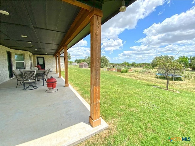 view of yard featuring a trampoline and a patio