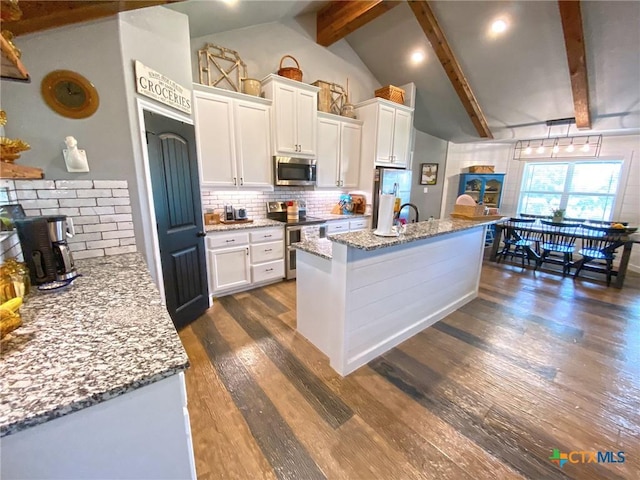 kitchen featuring beamed ceiling, stainless steel appliances, and white cabinetry