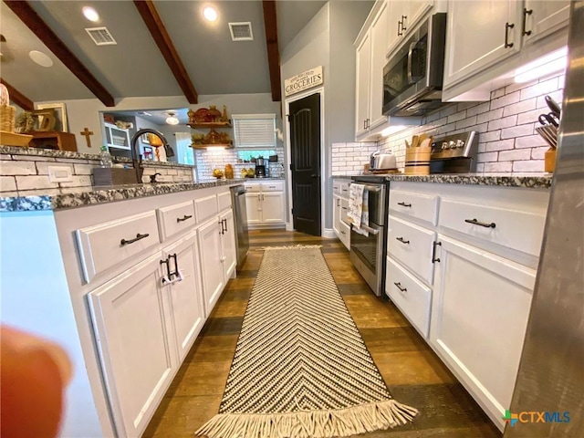 kitchen with visible vents, appliances with stainless steel finishes, dark stone counters, and dark wood finished floors