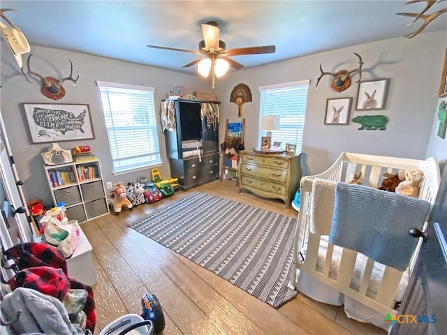 bedroom featuring multiple windows, wood-type flooring, and a ceiling fan