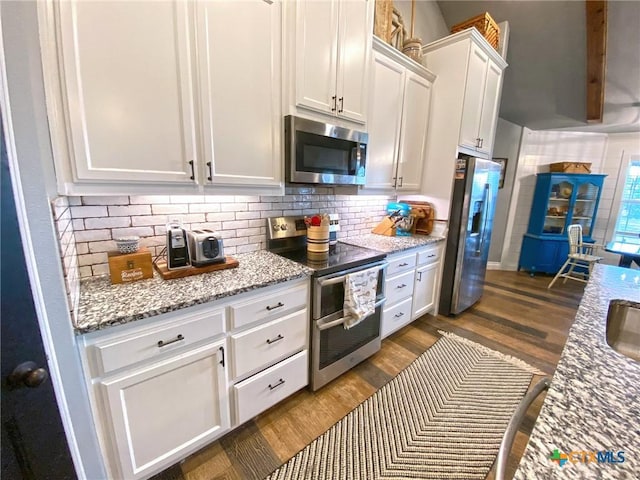 kitchen featuring light stone counters, stainless steel appliances, dark wood-style flooring, white cabinetry, and decorative backsplash