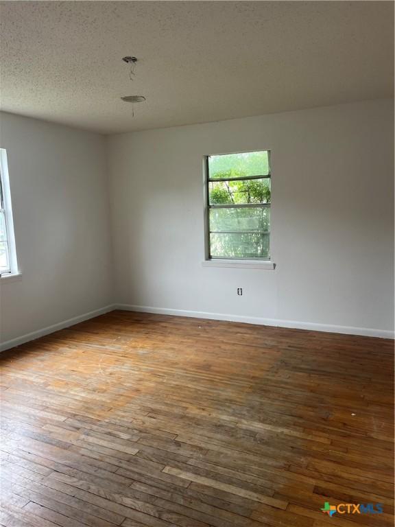 2110 Terrace Dr, Copperas Cove, TX 76522 - unfurnished room featuring baseboards, hardwood / wood-style floors, a healthy amount of sunlight, and a textured ceiling