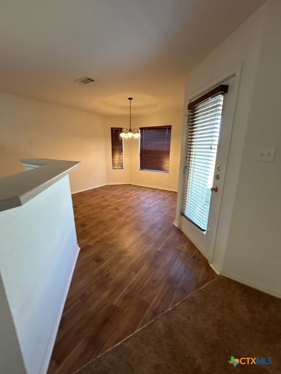 unfurnished living room featuring dark wood-type flooring and a notable chandelier