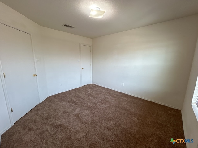 unfurnished bedroom with dark colored carpet