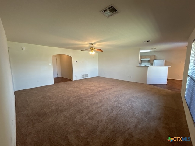 unfurnished living room with ceiling fan and dark colored carpet