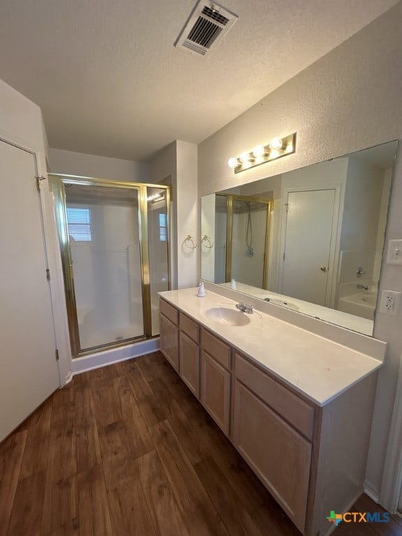 bathroom featuring vanity, a textured ceiling, hardwood / wood-style flooring, and a shower with door