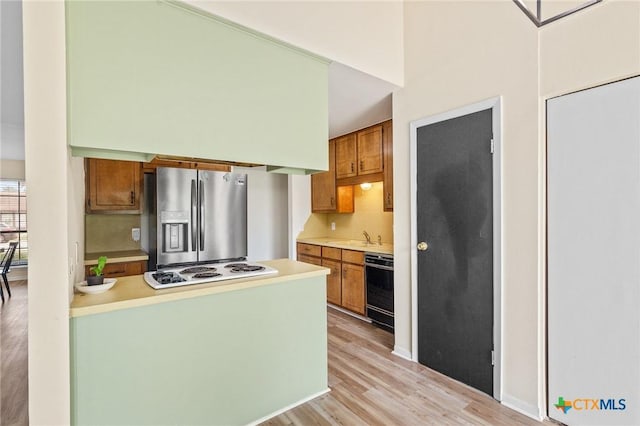 515 Camelot Dr, Victoria, TX 77901 - kitchen with stainless steel fridge with ice dispenser, white electric stovetop, light wood-style floors, light countertops, and brown cabinets