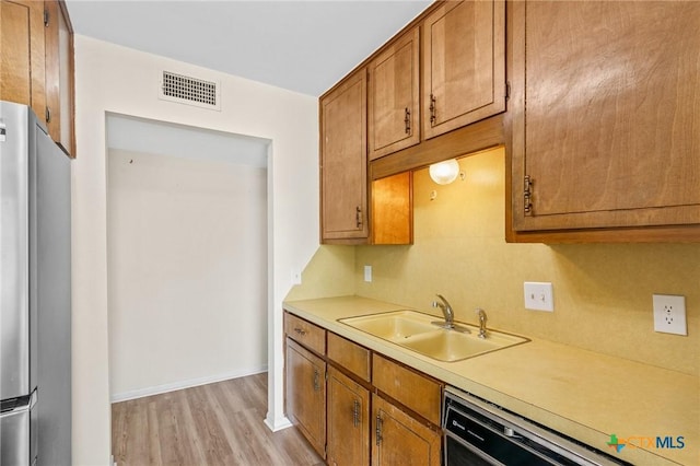 515 Camelot Dr, Victoria, TX 77901 - kitchen with dishwasher, light countertops, light wood-style flooring, brown cabinets, and freestanding refrigerator