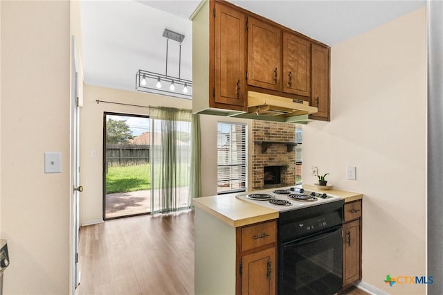 515 Camelot Dr, Victoria, TX 77901 - kitchen with white stovetop, under cabinet range hood, brown cabinets, light countertops, and light wood finished floors