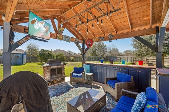 view of patio / terrace with a gazebo, a storage unit, an outdoor living space with a fireplace, and a grill