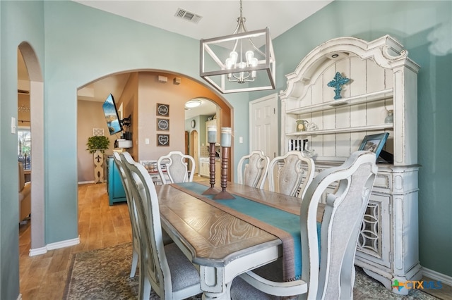 dining space featuring wood-type flooring and a notable chandelier