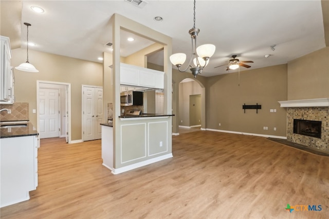 kitchen with white cabinetry, sink, tasteful backsplash, ceiling fan with notable chandelier, and decorative light fixtures