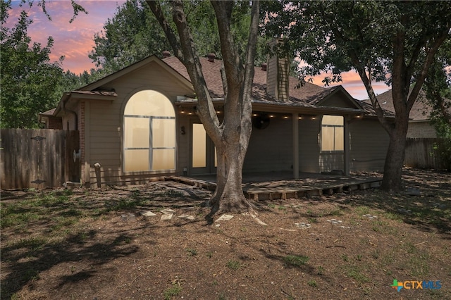 back house at dusk featuring a patio