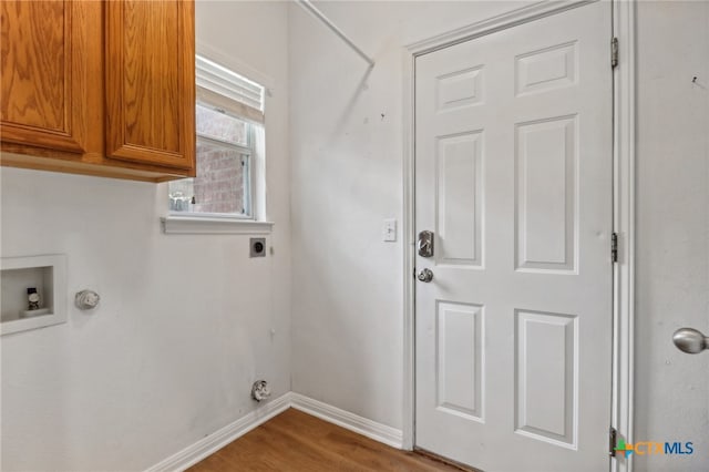 washroom with electric dryer hookup, washer hookup, cabinets, and wood-type flooring