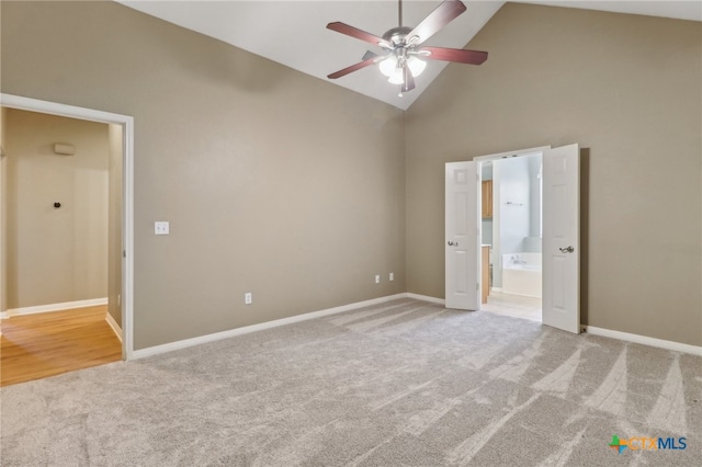 unfurnished bedroom featuring ceiling fan, ensuite bath, light carpet, and high vaulted ceiling