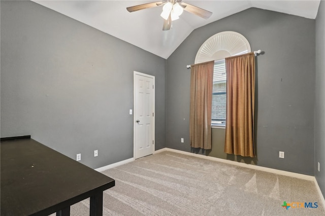 carpeted spare room featuring vaulted ceiling and ceiling fan