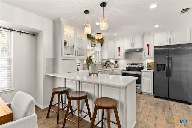 kitchen featuring visible vents, a sink, electric stove, under cabinet range hood, and refrigerator with ice dispenser