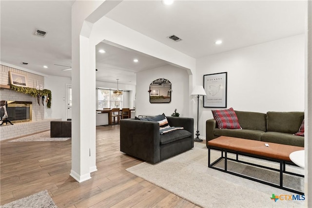 living room with recessed lighting, visible vents, light wood-style flooring, and a fireplace