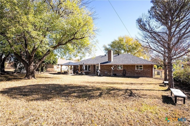 back of property featuring a gazebo, brick siding, and a chimney