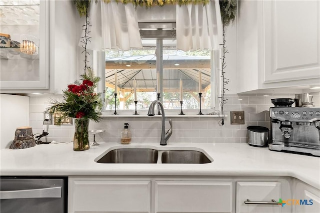 kitchen featuring dishwasher, light countertops, white cabinetry, and a sink