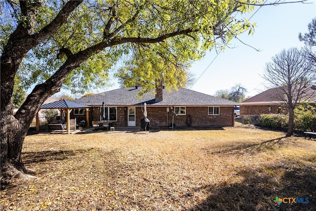 back of house with brick siding, a chimney, a gazebo, and a patio