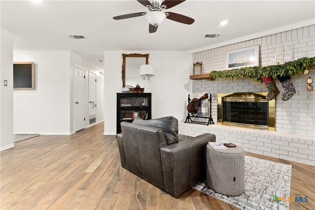 living room featuring visible vents, a fireplace, ceiling fan, and wood-type flooring