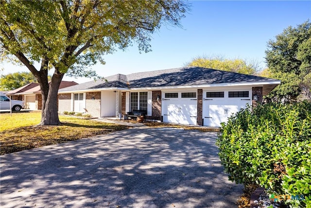 single story home featuring aphalt driveway, a garage, and brick siding