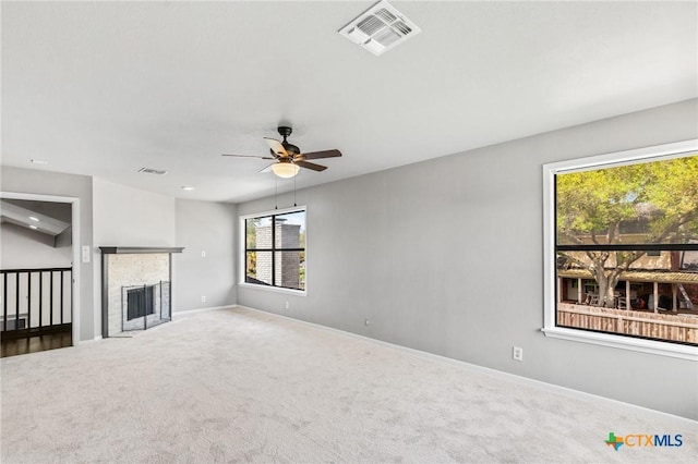 unfurnished living room featuring a fireplace with flush hearth, carpet floors, visible vents, baseboards, and ceiling fan