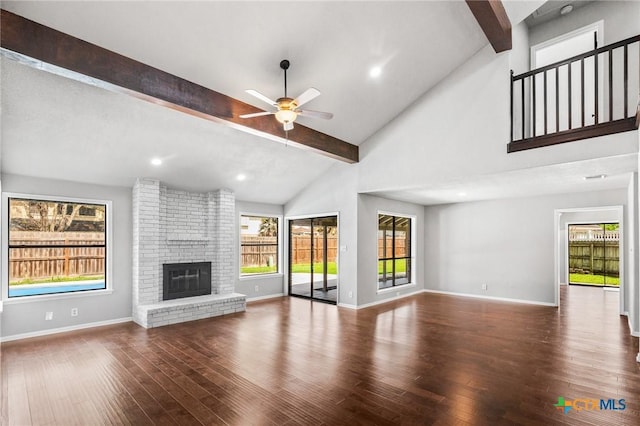 unfurnished living room with baseboards, beam ceiling, plenty of natural light, and wood finished floors