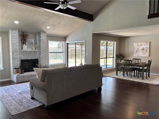 living room featuring beamed ceiling, a ceiling fan, a healthy amount of sunlight, and dark wood finished floors