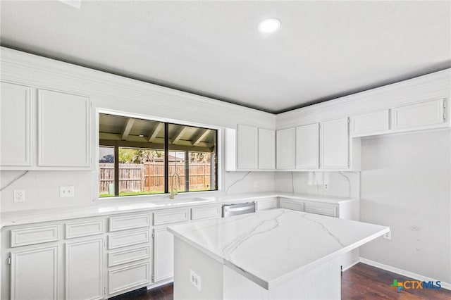 kitchen with a sink, stainless steel dishwasher, dark wood-style floors, and white cabinets