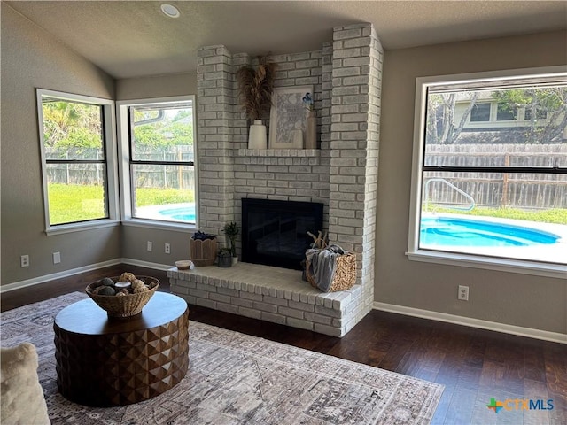 living area with plenty of natural light, baseboards, a fireplace, and hardwood / wood-style flooring