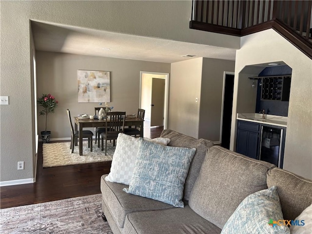 living room featuring wood finished floors, indoor wet bar, and baseboards