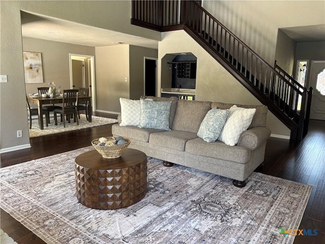 living area with baseboards, hardwood / wood-style floors, and stairway