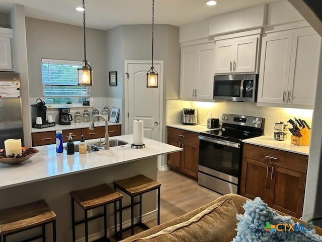 kitchen featuring stainless steel appliances, a breakfast bar, light countertops, tasteful backsplash, and recessed lighting