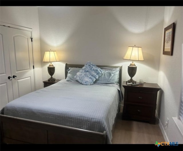 bedroom with wood finished floors, a closet, and baseboards