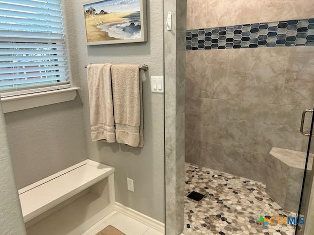 bathroom with a stall shower, tile patterned floors, and baseboards