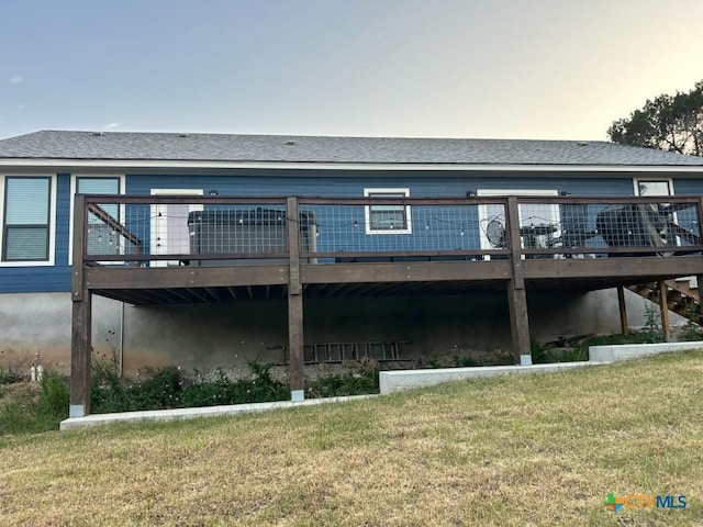 back of house with a deck and a lawn