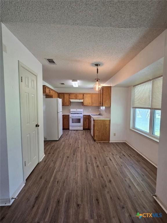 4709 Poppy Wood Cir, Killeen, TX 76542 - kitchen featuring white appliances, dark wood-type flooring, brown cabinetry, light countertops, and a textured ceiling