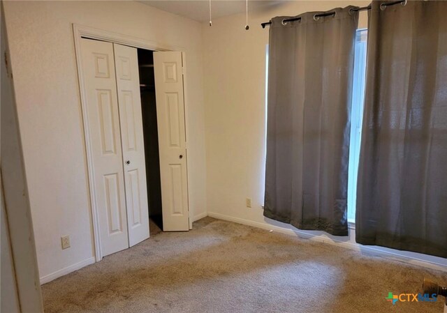 unfurnished bedroom featuring a closet and light carpet