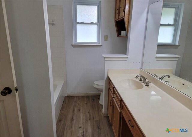 full bathroom featuring toilet, vanity, wood-type flooring, and tiled shower / bath